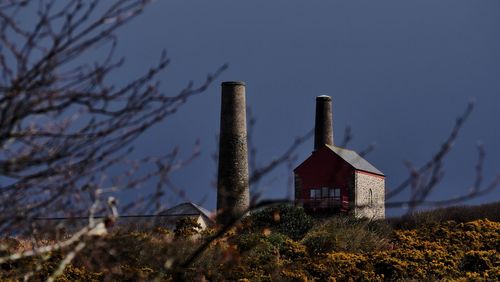 Silos by barn on field against sky