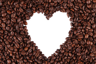 High angle view of coffee beans arranged in heart shape against white background