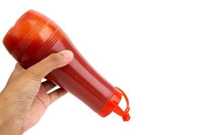 Close-up of hand holding bottle against white background