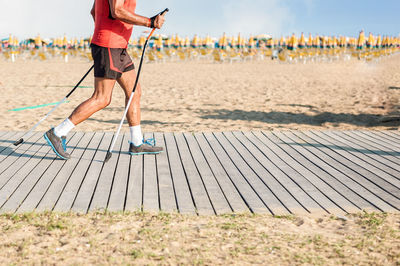 Low section of hiker walking on boardwalk against sky