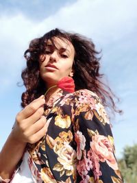 Young woman with floreale pattern dress holding a poppy flower