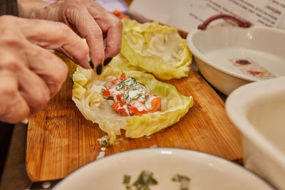 Chef makes cabbage rolls with salmon, carrots and sauce in the kitchen. french recipe