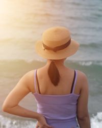 Rear view of woman wearing hat standing at beach