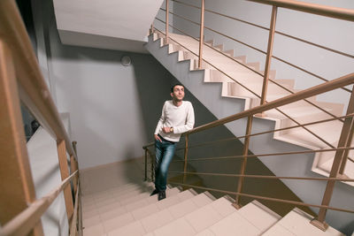 Portrait of young man standing on staircase