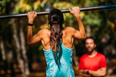 Woman doing pull-ups in the park with personal trainer