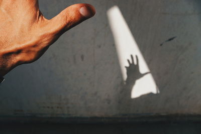 Shadow of cropped hand on concrete wall