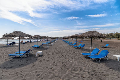 Deck chairs on beach against sky