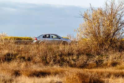 Abandoned car on field against sky