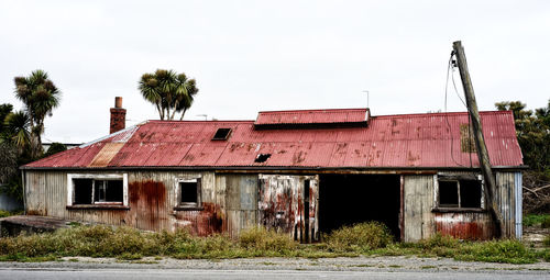 Old house on grassy field against sky