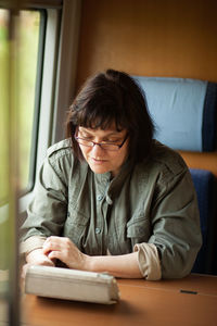 Mature woman using digital tablet in train