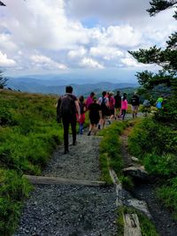 Rear view of people walking on road against sky