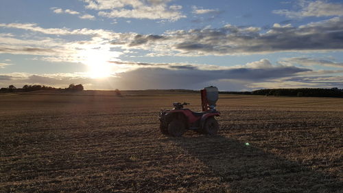 Quadbike at farm against cloudy sky during sunset