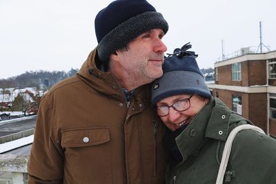 Happy couple against buildings in city at winter