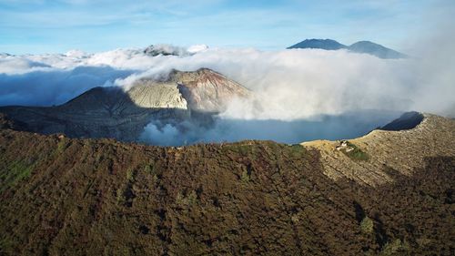 Smoke emitting from volcanic landscape against sky