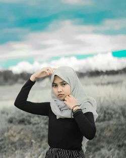 Portrait of a young woman standing on field