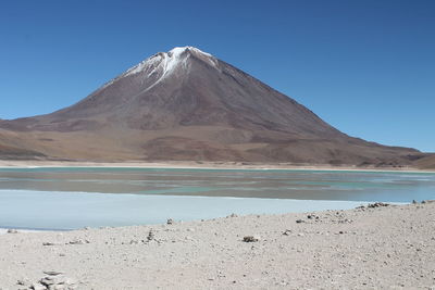 Scenic view of lake and mountains against clear blue sky