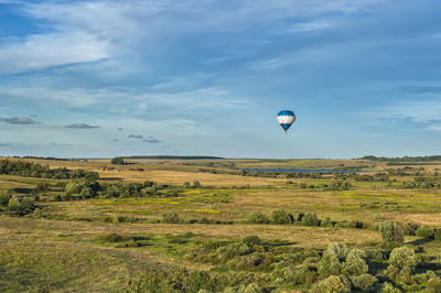 Hot air balloons on field against sky