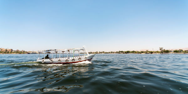 Boat sailing in sea against clear sky