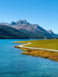 Scenic view of sea and mountains against clear blue sky