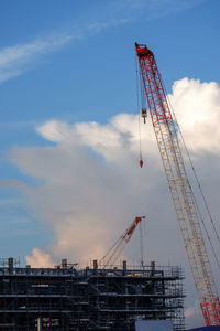 Low angle view of cranes at construction site against sky