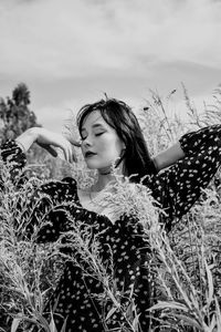 Portrait of young woman standing against sky