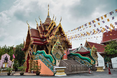 Guardian nagas, flags and colorful decorated entrance of wat nak prok, the naga temple