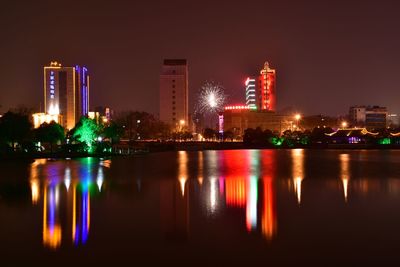 Illuminated cityscape against sky at night