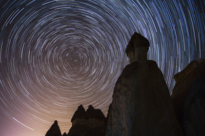 Low angle view of silhouette rock formation against sky at night