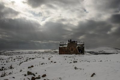 Built structure on landscape against cloudy sky