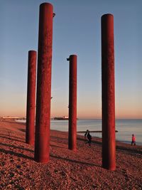 Metal  posts on beach against clear sky at sunset