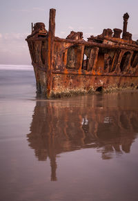 Abandoned boat on sea against sky