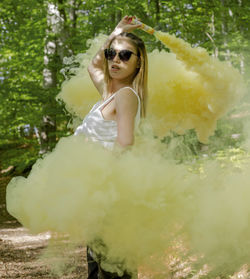 Portrait of woman wearing sunglasses while holding distress flare