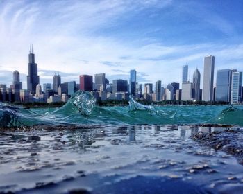 Tilt-shift image of waves in sea by cityscape