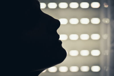 Close-up portrait of silhouette woman against illuminated lights