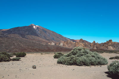 Scenic view of arid landscape against clear blue sky