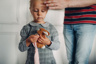 Midsection of father with daughter standing against wall