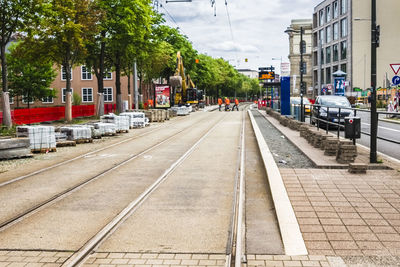 Railroad tracks by road in city against sky