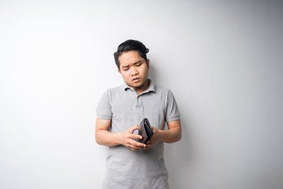 Man holding camera while standing against white background