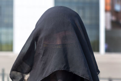 Portrait of a muslim woman in national clothes covering her face european city.