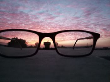 Close-up of sunglasses against sky during sunset