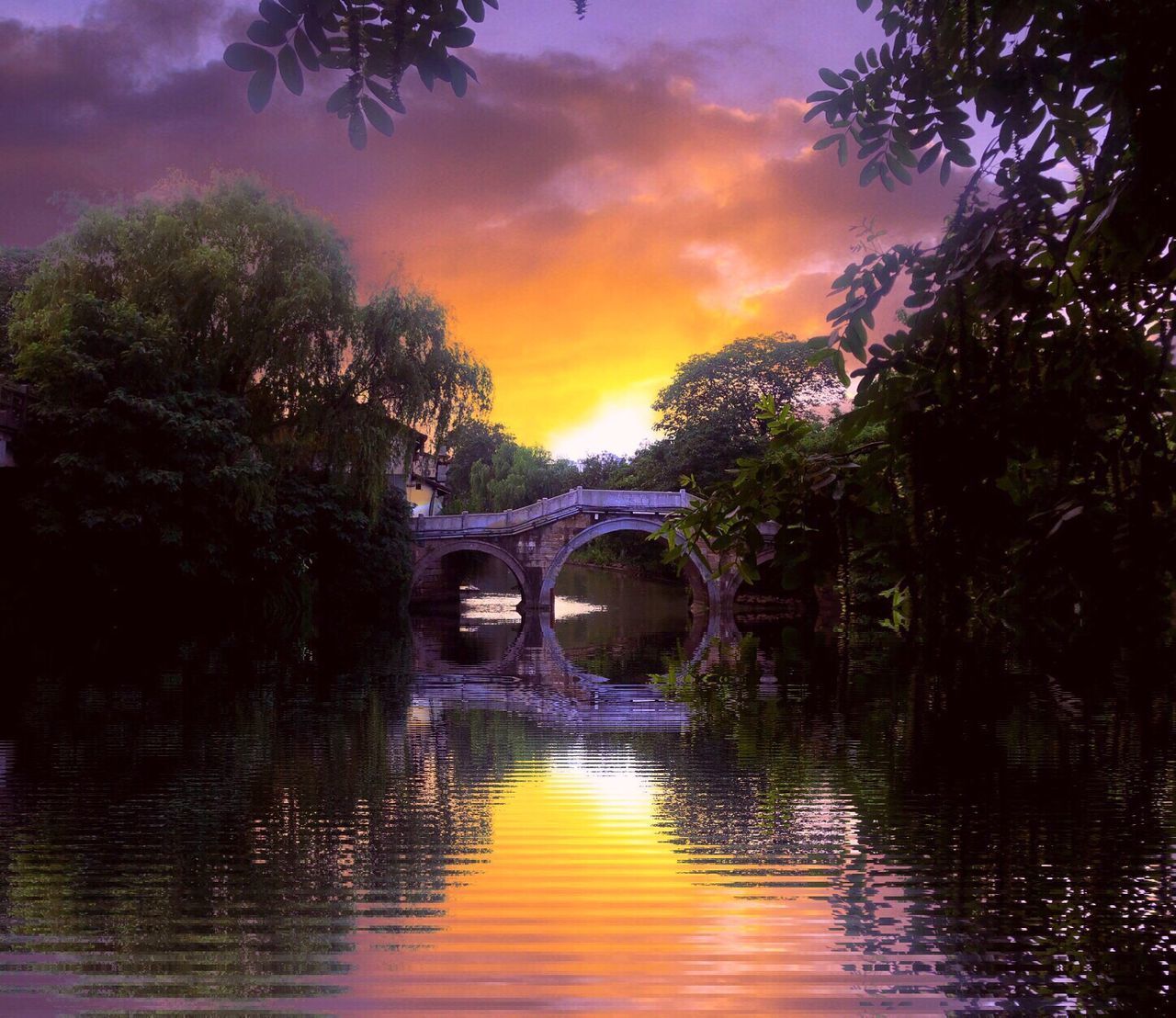 BRIDGE OVER RIVER AGAINST SKY AT SUNSET