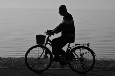 Side view of man riding bicycle on lake