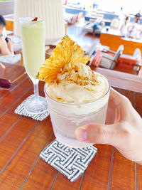 Close-up of hand holding drink on table