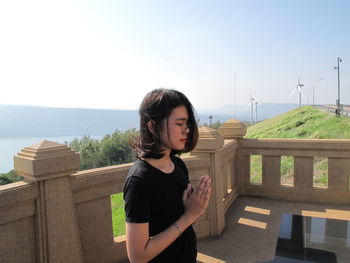 Woman standing by railing against sky