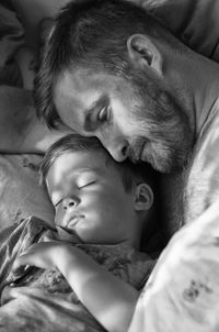 High angle view of father and son resting on bed