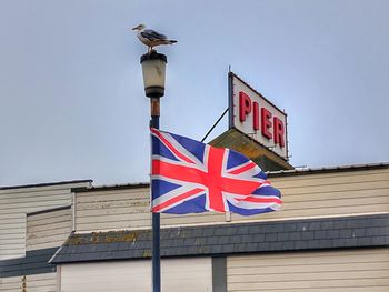 Low angle view of flag against building against sky