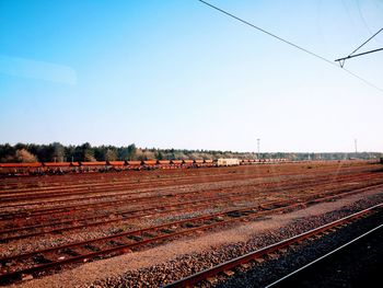 Railroad tracks on field against clear sky