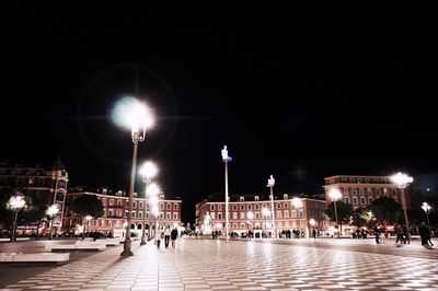 People walking on illuminated street at night