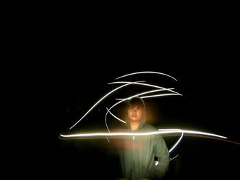 Portrait of light trails against black background