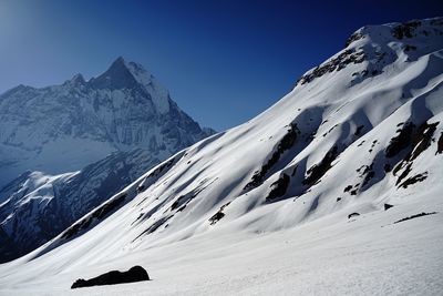 Scenic view of snow covered mountains against clear sky